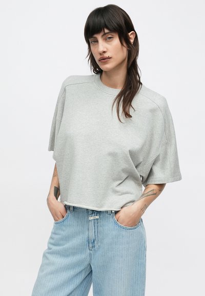 Sweat-shirt gris court avec manches courtes, encolure arrondie et coupe décontractée, porté avec un jean taille haute bleu clair.