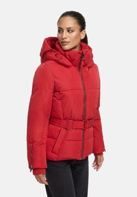 Red padded jacket with a belted waist, high collar, and adjustable hood. Features zippered pockets and a smooth synthetic texture.