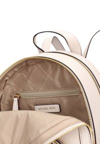 Zaino Michael Kors, pelle martellata bianca, cerniera dorata, interno beige, tasca interna con zip, etichetta marchiata all'interno, forma arrotondata.