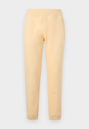 Ανοιχτό κίτρινο στενό παντελόνι φόρμας με ελαστική μέση και μανσέτες στους αστραγάλους, με διακριτικό λευκό λογότυπο Adidas trefoil στο αριστερό μηρό.