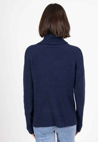 Pull en maille côtelée bleu marine avec un col montant, des manches longues et une coupe décontractée. Le dos présente un design sans coutures et des fentes sur les côtés.