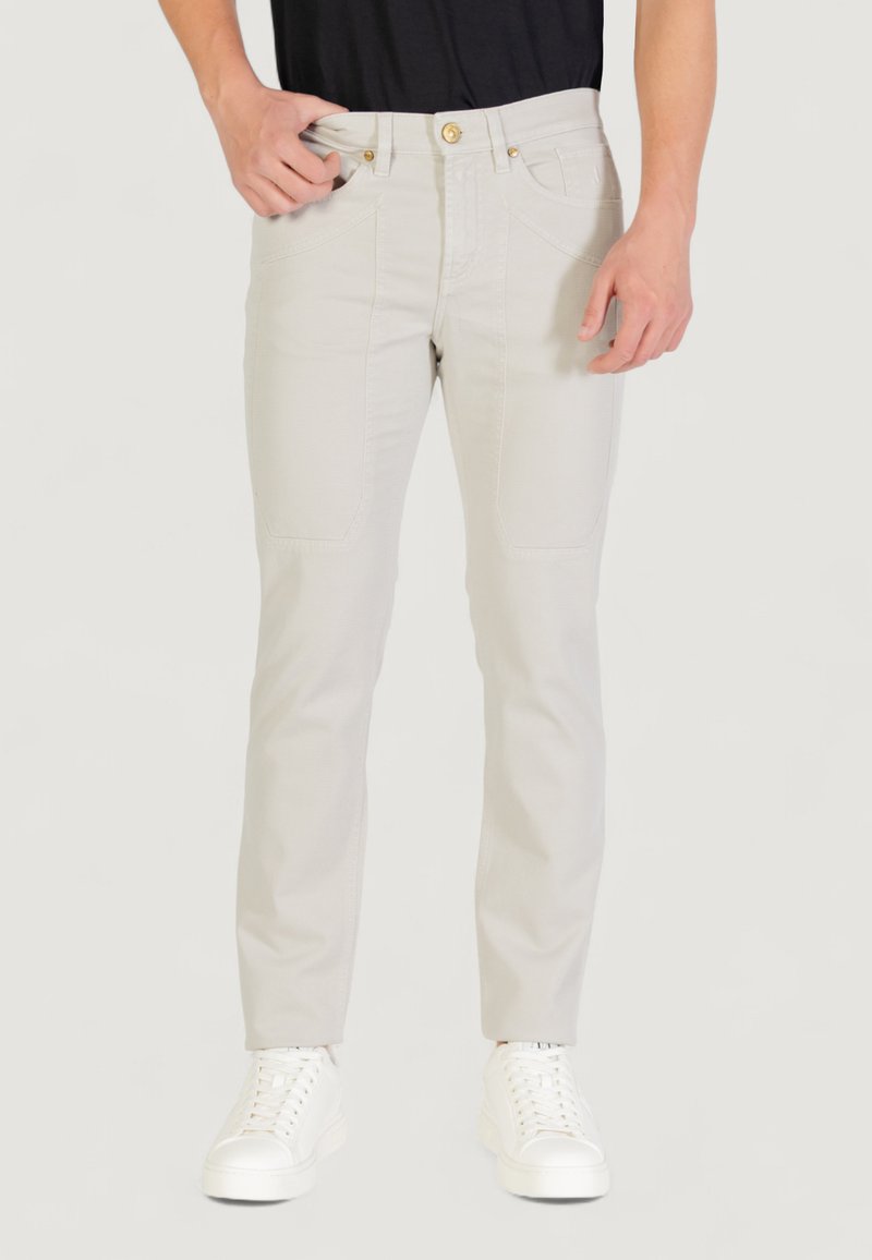 Pantalon gris clair avec une coupe ajustée, en mélange de coton. Présente des poches discrètes et un bouton supérieur doré. Associé à des baskets blanches.