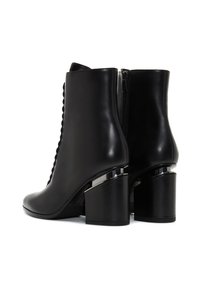 Par de botas de cuero negro hasta el tobillo con tacones en bloque y cremalleras laterales, mostrando vistas trasera y lateral izquierda sobre fondo blanco.