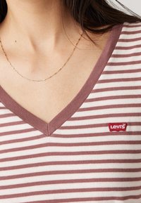 V-neck t-shirt with horizontal maroon and white stripes, made of soft fabric. Features a small red Levi's logo on the left side.