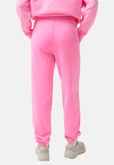 Rosafarbene Sweatpants aus weichem Material, mit einem elastischen Bund und Bündchen, versehen mit einem kleinen Logosticker auf der Rückseite.