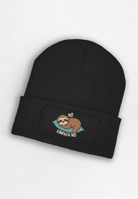 Black knit beanie featuring a patch with a sloth illustration on a turquoise pillow, text above and below in white, reading "NÖ EINFACH NÖ."