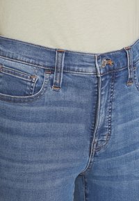 Jeans i denim i medelblå färg med en lätt blekning. Funktioner inkluderar en klassisk femfickdesign, bältesslingor och kontrasterande sömmar.