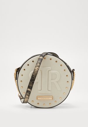 Okrągła beżowa torebka z wytłoczonym logo "ATR", złotymi ćwiekami na krawędzi oraz paskiem w wężowy wzór z złotym łańcuszkiem.