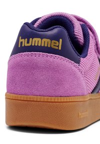 Fioletowy zamszowy i siateczkowy sneaker z gumową podeszwą w kolorze karmelu, z złotym logo "hummel" i teksturowanymi akcentami na pięcie.