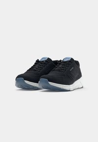 Paire de baskets de sport noires en mesh avec semelles blanches et accents bleu clair, légèrement inclinées vers la droite sur un fond uni.
