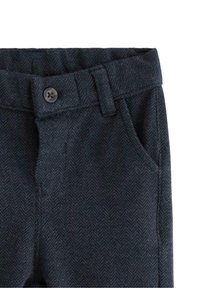 Mörkblå byxor i fiskbensmönster med knäppning, bältesöljer och sidofickor. Tjänlig textil med en förfinad yta.