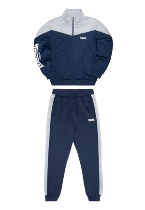 Sinine dressipluus, millel on lukuga jakk hallide aktsentide ja logoga. Pükstel on nööriga vöökoht ja küljetaskud, sobiv disain.