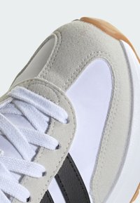 Sivý semiš a biely sieťový teniska s bielymi šnúrkami, čiernymi pruhmi a gumenou podrážkou. Detailný pohľad na vrchné detaily topánky.