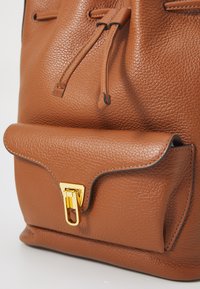 Borsa in pelle marrone con superficie testurizzata, chiusura con cordoncino e patta frontale con fibbia in tono oro.
