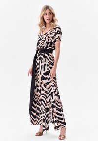 Robe maxi en imprimé animal noir et beige, avec un décolleté en V, un tissu doux, des manches larges et une ceinture noire accentuant la taille.
