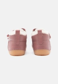 Rosa Lederschuhe mit einem weichen weißen Futter aus Fell, ausgestattet mit zwei Rückenschlaufen. Gummisohlen und genähte Details sorgen für Langlebigkeit.