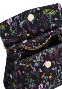 Crna torba s printom šarenog cvijeća i insekata, zlatni magnetski kopča i zlatna lančana naramenica djelomično vidljiva unutra.