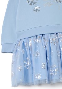 Vestido de manga larga en azul claro con parte superior ajustada y falda de tul en capas. La falda presenta patrones de copos de nieve plateados. Textura de tela suave.