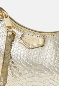 Guldfarvet metallic håndtaske med et struktureret slangemønster, en lynlåslukning og et brandet guldfarvet hardware element.