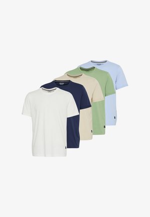 Beige Baumwoll-T-Shirt in Kombination mit dunkelblauen Shorts, im entspannten Schnitt. Tragend mit weißen Socken und cremefarbenen Sneakers mit Akzenten.
