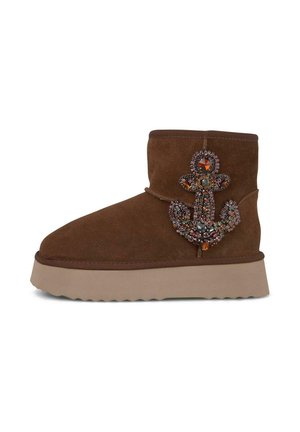 Bottines en suède marron avec une semelle épaisse et claire, arborant un design d'ancre ornée de bijoux sur le côté extérieur.