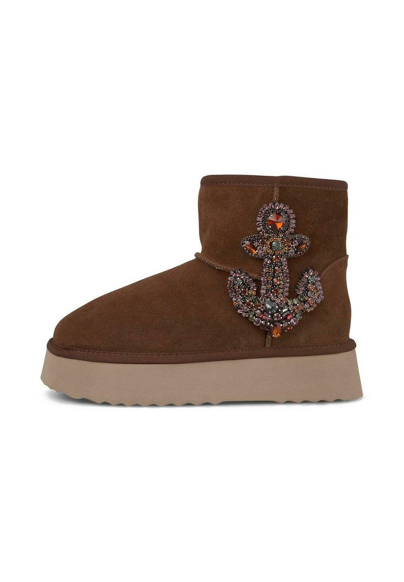 Bottines en suède marron avec une semelle épaisse et claire, arborant un design d'ancre ornée de bijoux sur le côté extérieur.