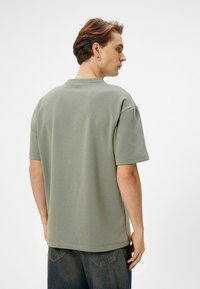 Camiseta de algodón verde claro con mangas cortas, cuello redondo y un ajuste relajado. Textura suave, diseño minimalista y sin patrones o gráficos visibles.
