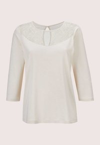 Crèmekleurige top met driekwartmouwen, een kanten paneel op de schouders en een keyhole-opening aan de achterkant, met een zachte textuur.