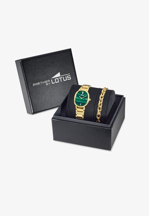 Reloj de tono dorado con esfera verde y pulsera enlazada, presentado en una caja de regalo negra texturizada con texto de logo y interior acolchado.