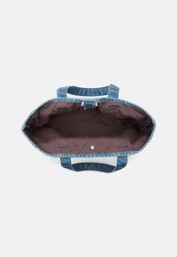 Denim tote taske med to håndtag, med en dyb brun indlægning og trykknaplukning. Indersiden har lommer til organisering.