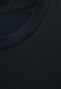 Tela de camiseta de algodón negra que muestra un primer plano del cuello. Textura suave con un sutil patrón de espiga y un escote redondo.