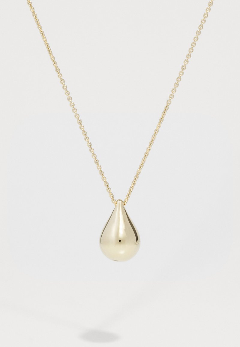 Collier en or avec un pendentif en forme de goutte d'eau, à la surface lisse et brillante, et un petit point noir, suspendu à une chaîne délicate.