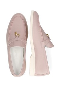 Mocassini in pelle rosa chiaro con suola piatta in gomma bianca, caratterizzati da un accento dorato sulla parte anteriore e da un motivo cucito lungo il bordo superiore.