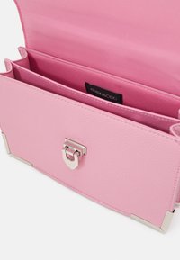 Rosa strukturierte Handtasche mit silberner Hardware. Das Innere verfügt über zwei Fächer und ein markiertes Etikett. Entworfen mit einem sicheren Verschluss.