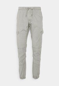 Pantaloni cargo jogger grigi chiari con vita elastica, cordoncino, tasche laterali con pattina, cuciture sulle ginocchia e polsini elasticizzati su uno sfondo bianco.