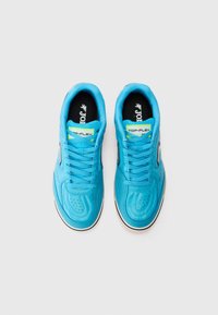 Zapatillas deportivas azules con parte superior suave, cuello acolchado, diseño perforado, cordones planos, acentos negros en contraste y detalle del logo en la lengua.