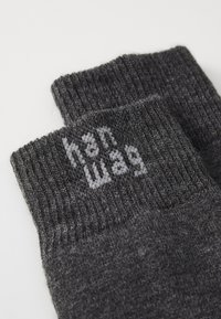 Sive volnene nogavice z rebrastim vrhom, ki na manšeti nosijo blagovno znamko "hanwag" v svetlo sivi pletenini. Mehka tekstura in trdna zasnova.