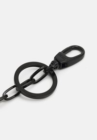 Accessorio a catena nera che presenta due anelli interconnessi e un clip robusto. Texture liscia con una finitura lucida, ideale per fissare oggetti.
