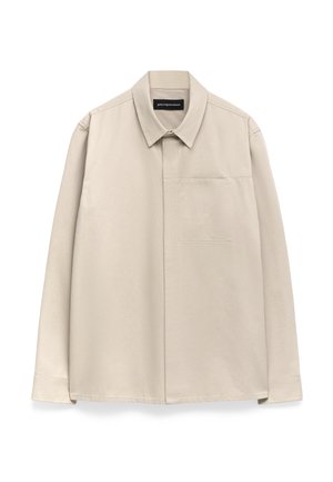 Chemise longue à manches beiges clairs avec un col classique, une poche poitrine unique et un tissu légèrement texturé. Poignets boutonnés et ourlet droit.