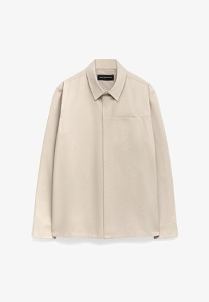 Chemise longue à manches beiges clairs avec un col classique, une poche poitrine unique et un tissu légèrement texturé. Poignets boutonnés et ourlet droit.