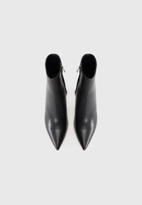 Black leather ankle boots with pointed toes, smooth texture, and side zippers. Minimalist design, seamless top edges.