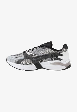 Zapatillas deportivas con parte superior de malla en blanco y negro con un patrón geométrico, cuello acolchado y suela de goma texturizada.