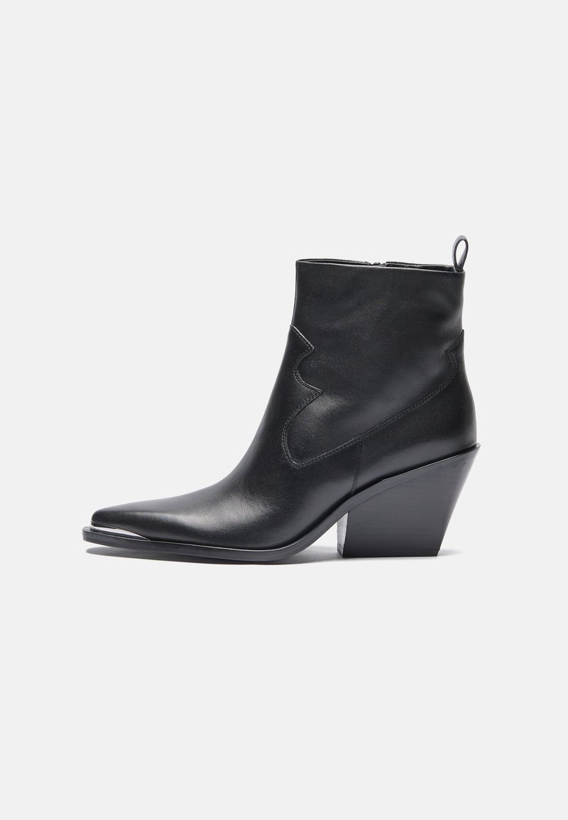 Bottine en cuir noir avec un bout pointu, un discret motif de couture western, et un talon empilé. Fermeture éclair sur le côté et une languette de traction.