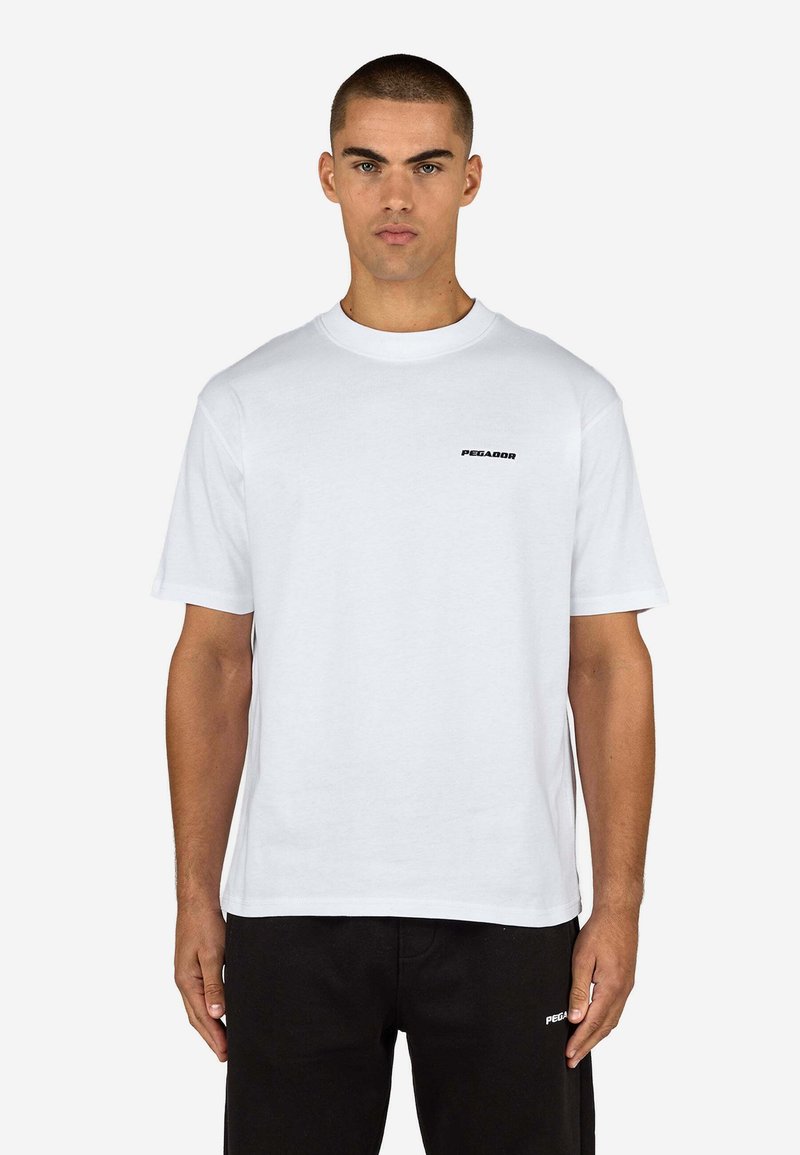 Weißes kurzärmliges Baumwoll-T-Shirt mit rundem Ausschnitt und kleinem schwarzem "PEGADOR"-Logo auf der linken Brust. Einfaches, klares Design.