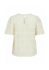 Blusa color crema con un patrón de rejilla texturizado, mangas cortas abullonadas y una abertura en forma de llave en la parte posterior.