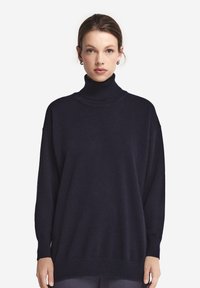 Marinblå turtleneck-tröja med avslappnad passform, ribbade ärmslut och nederkant. Tillverkad av mjukt, texturerat tyg, med sänkt axel för en avslappnad stil.