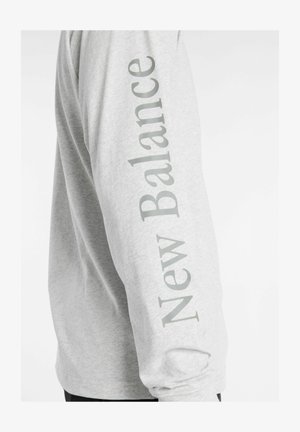Long-sleeve gray shirt featuring "New Balance" printed vertically in light gray along the left sleeve; cotton blend fabric.