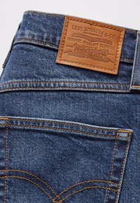 Poche arrière d'un jean en denim bleu avec une étiquette en cuir marron Levi Strauss & Co. cousue au-dessus de la poche.