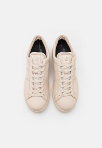 Beiga lädersneakers med en slät yta, rund tå och platta snörningar. Har en minimalistisk design och en logotyp på tungan.