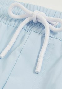 Șorturi de baie de culoare albastru deschis, cu un elastic la talie, prevăzute cu un șnur alb și capete din plastic. Material neted cu detalii de cusătură subtile.